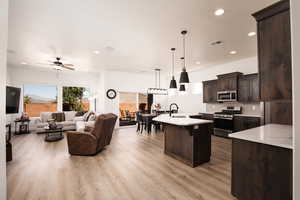 Kitchen with decorative light fixtures, stainless steel appliances, backsplash, a kitchen island with sink, and recessed lighting