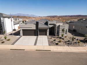 View of front of house with a garage, stucco siding, driveway, a mountain view, and a residential view