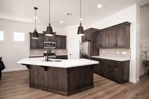 Kitchen featuring dark brown cabinetry, stainless steel appliances, tasteful backsplash, decorative light fixtures, and recessed lighting
