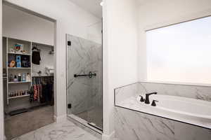 Full bathroom with a garden tub, a marble finish shower, a spacious closet, and marble look tile flooring