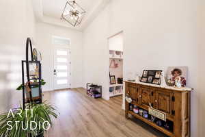Entrance foyer with a towering ceiling, light wood-style flooring, a raised ceiling, and a chandelier