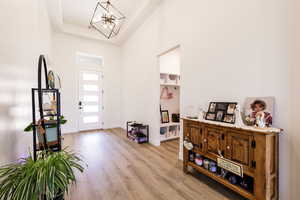 Foyer featuring a high ceiling, light wood finished floors, a tray ceiling, and a chandelier