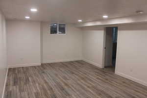 Finished basement with wood finished floors and recessed lighting