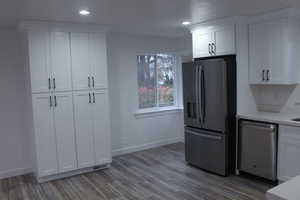 Kitchen with appliances with stainless steel finishes, white cabinetry, dark wood-style floors, recessed lighting, and light stone counters