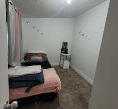 Bedroom with dark colored carpet and a textured ceiling
