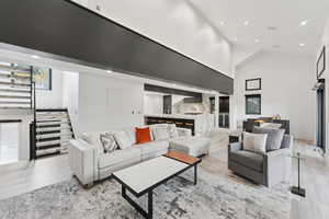 Living room featuring stairway, a towering ceiling, recessed lighting, and light wood-type flooring