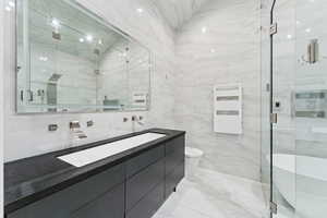 Full bathroom featuring tile walls, a freestanding tub, a marble finish shower, double vanity, and light marble finish floors