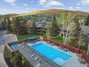 Community pool with a patio, a mountain view, a fenced backyard, and a residential view