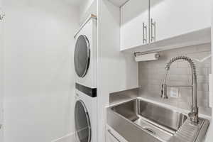 Washroom featuring a sink and stacked washing machine and dryer