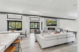 Living area featuring a lit fireplace, light wood finished floors, and recessed lighting