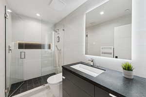 Full bath featuring vanity, a shower stall, tile walls, and radiator heating unit
