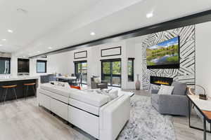 Living area with light wood finished floors, a large fireplace, and recessed lighting