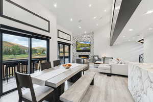 Dining area featuring a warm lit fireplace, a towering ceiling, french doors, recessed lighting, and light wood finished floors