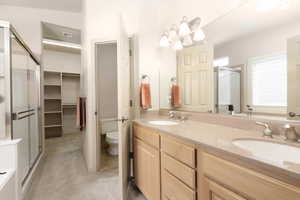 Full bath featuring double vanity, a shower stall, light colored carpet, and a spacious closet