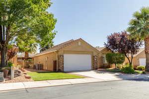 View of front of property featuring stucco siding, driveway, an attached garage, and stone siding