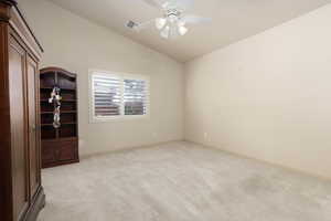 Spare room featuring lofted ceiling, light colored carpet, and a ceiling fan