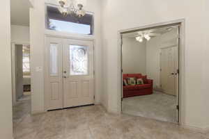 Foyer featuring a ceiling fan, light carpet, a chandelier, and light tile patterned floors