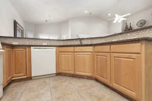 Kitchen with dishwasher, light tile patterned flooring, hanging light fixtures, a ceiling fan, and a chandelier