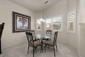 Dining room with light carpet and vaulted ceiling