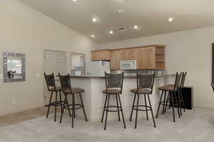 Kitchen with dark countertops, a kitchen bar, white appliances, a peninsula, and open shelves