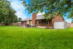Rear view of house featuring a fenced backyard, a patio, brick siding, and a chimney