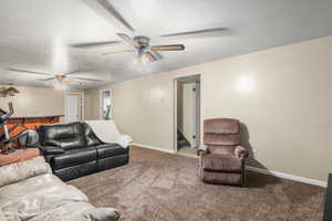 Carpeted living area featuring a textured ceiling, stairway, and a ceiling fan