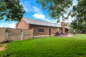Rear view of property with a gate, roof with shingles, a patio area, brick siding, and a chimney