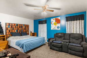 Carpeted bedroom with a textured ceiling and a ceiling fan
