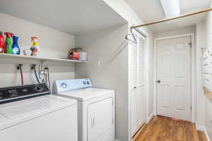 Washroom with wood finished floors and separate washer and dryer