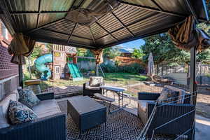 Fenced backyard with a playground, a patio, a gazebo, and an outdoor living space
