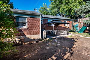 Rear view of property featuring a gazebo, a patio area, brick siding, a playground, and an outdoor hangout area