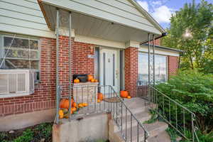 Property entrance featuring brick siding, a porch, and cooling unit