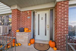 Entrance to property with brick siding and a porch