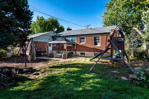 Rear view of property with a gazebo, a playground, a patio area, brick siding, and a chimney