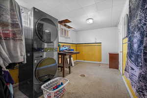Washroom with stacked washing machine and dryer and baseboards