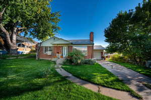 View of front of house featuring brick siding, a chimney, driveway, and an attached garage