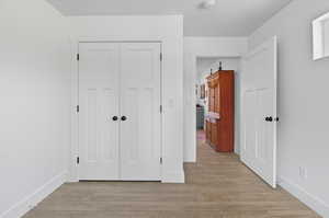 Unfurnished bedroom featuring light wood finished floors and a closet