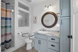 Full bathroom with dark wood-style floors, vanity, and a shower stall