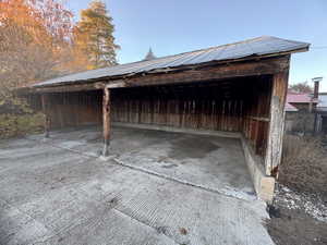 View of vehicle parking with a pole building and a carport