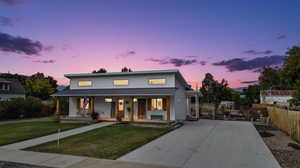 Modern farmhouse with a porch, a lawn, a metal roof, a standing seam roof, and concrete driveway