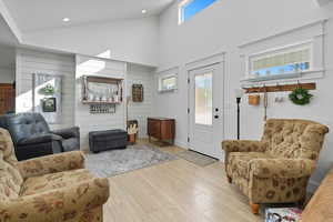Living room with high vaulted ceiling, wood finished floors, wood walls, and recessed lighting