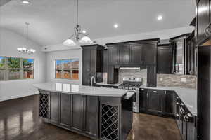 Kitchen with decorative backsplash, gas range, decorative light fixtures, recessed lighting, and lofted ceiling