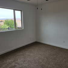 Spare room featuring carpet and ceiling fan
