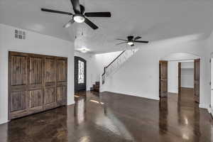 Entrance foyer featuring arched walkways, stairway, and a ceiling fan
