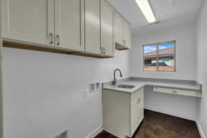 Laundry area with washer hookup, cabinet space, and a textured ceiling
