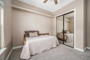 Carpeted bedroom featuring a ceiling fan and a closet