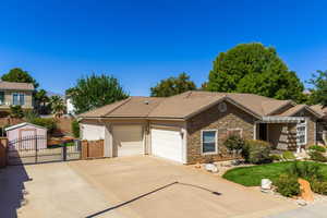 Ranch-style house featuring a gate, stone siding, concrete driveway, a tiled roof, and a garage