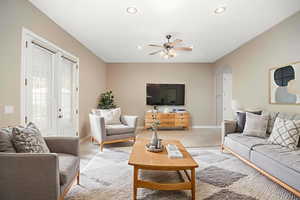 Living room with arched walkways, carpet floors, recessed lighting, a ceiling fan, and french doors