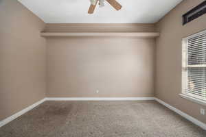 Carpeted spare room with ceiling fan and baseboards