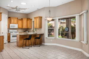 Kitchen featuring white appliances, a kitchen bar, pendant lighting, light tile patterned floors, and light countertops